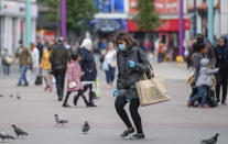 A shopper wearing a face mask on Humberstone Gate in Leicester, England, Monday June 29, 2020. The British government is reimposing lockdown restrictions in the central England city of Leicester after a spike in coronavirus infections, including the closure of shops that don’t sell essential goods and schools. (Joe Giddens/PA via AP)