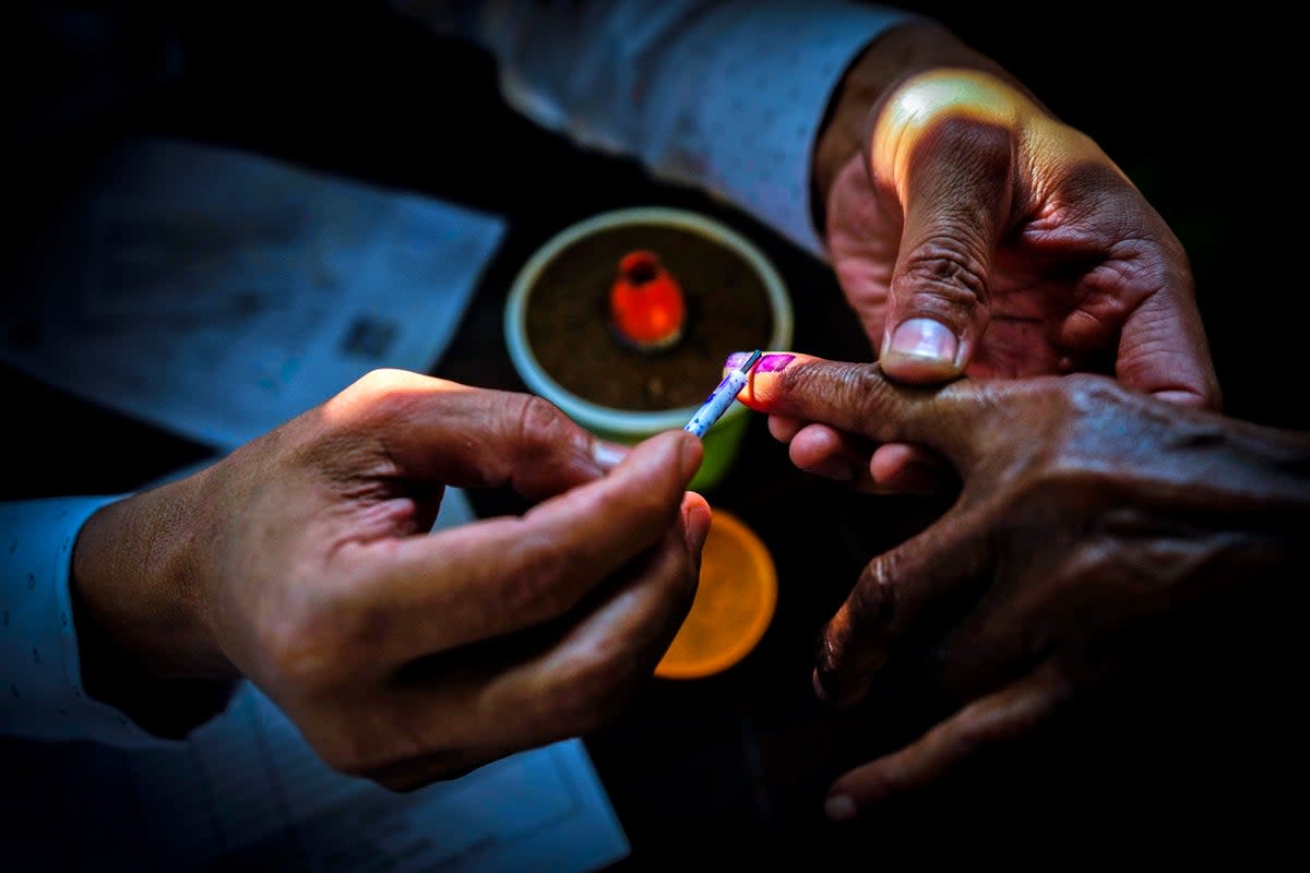 A polling official puts indelible ink mark on the index finger of woman during the second round of voting in the six-week-long national election in Morigaon district (AP)