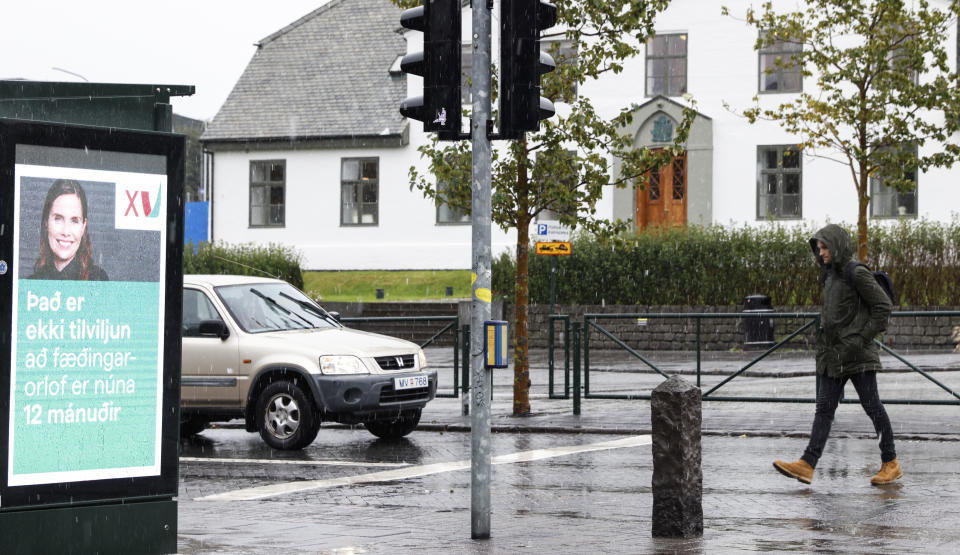 A man walks toward an election poster from the Left Green Party, showing Prime Minister Katrin Jakobsdottir and saying "It isn't coincidence that maternity leave is now 12 months" in Reykjavik, Iceland, Wednesday, Sept. 22, 2021. Climate change is top of the agenda when voters in Iceland head to the polls for general elections on Saturday, following an exceptionally warm summer and an election campaign defined by a wide-reaching debate on global warming. Polls suggest Prime Minister Katrin Jakobsdottir's Left Green Party could face a poor outcome, ending the current coalition. (AP Photo/Brynjar Gunnarsson)