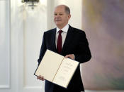 New elected German Chancellor Olaf Scholz holds his letter of appointment presented by German President Frank-Walter Steinmeier during a reception at Bellevue Palace in Berlin, Germany, Wednesday, Dec. 8, 2021. Scholz has become Germany's ninth post-World War II chancellor, opening a new era for the European Union’s most populous nation and largest economy after Angela Merkel’s 16-year tenure. Scholz’s government takes office with high hopes of modernizing Germany and combating climate change but faces the immediate challenge of handling the country’s toughest phase yet of the coronavirus pandemic. (AP Photo/Michael Sohn)
