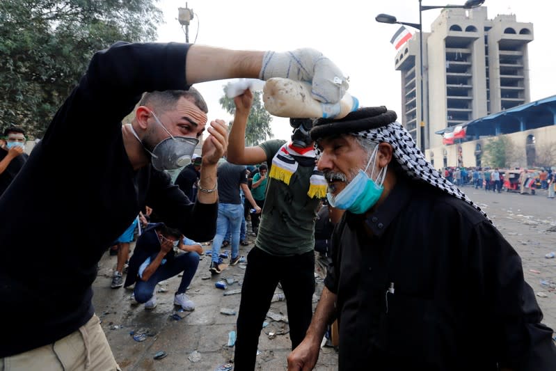 A demonstrator pours water over a man's head during a protest over corruption, lack of jobs, and poor services, in Baghdad