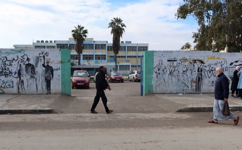 People walk near a school run by UNRWA at Baqaa Palestinian refugee camp, near Amman