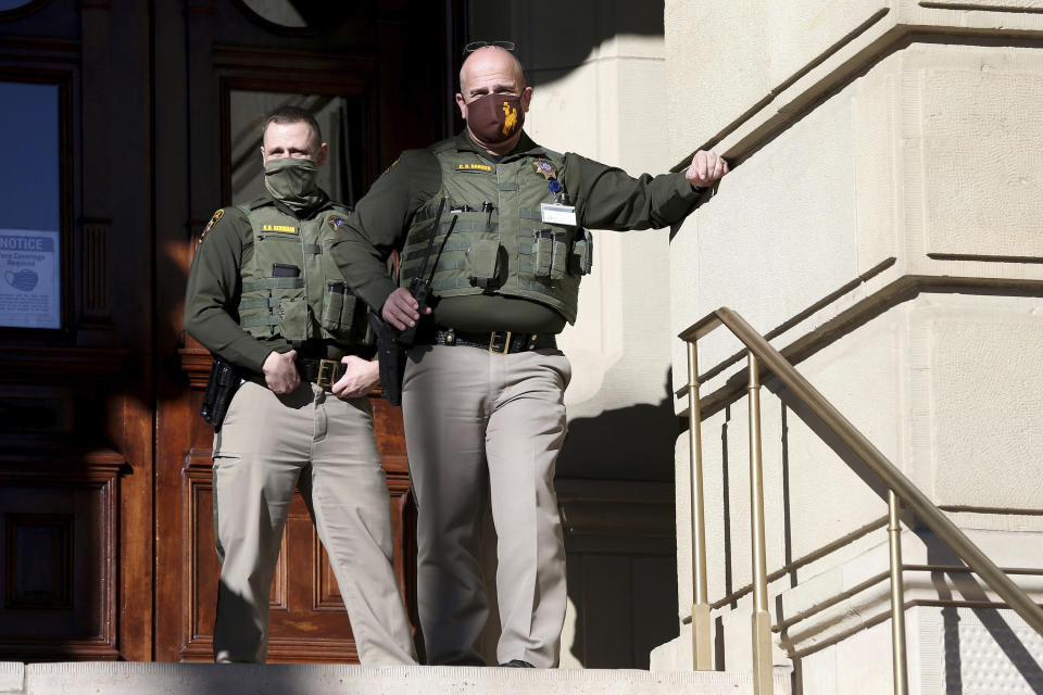 In this Wednesday, Jan. 6 2021, photo, Wyoming Highway Patrol troopers watch hundreds gather for a Stop the Steal rally, on the steps the Wyoming State Capitol Building in Cheyenne, Wyo. Wyoming Gov. Mark Gordon quietly mobilized dozens of National Guard troops in case of any violence at the state Capitol in Cheyenne in January. The deployment came to light Friday, March 5, 2021, after an Associated Press inquiry after the Jan. 6 riot at the U.S. Capitol, which left five dead. (Michael Cummo/The Wyoming Tribune Eagle via AP)