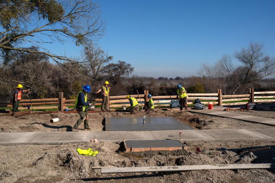 Workers put up fencing and concrete pads.