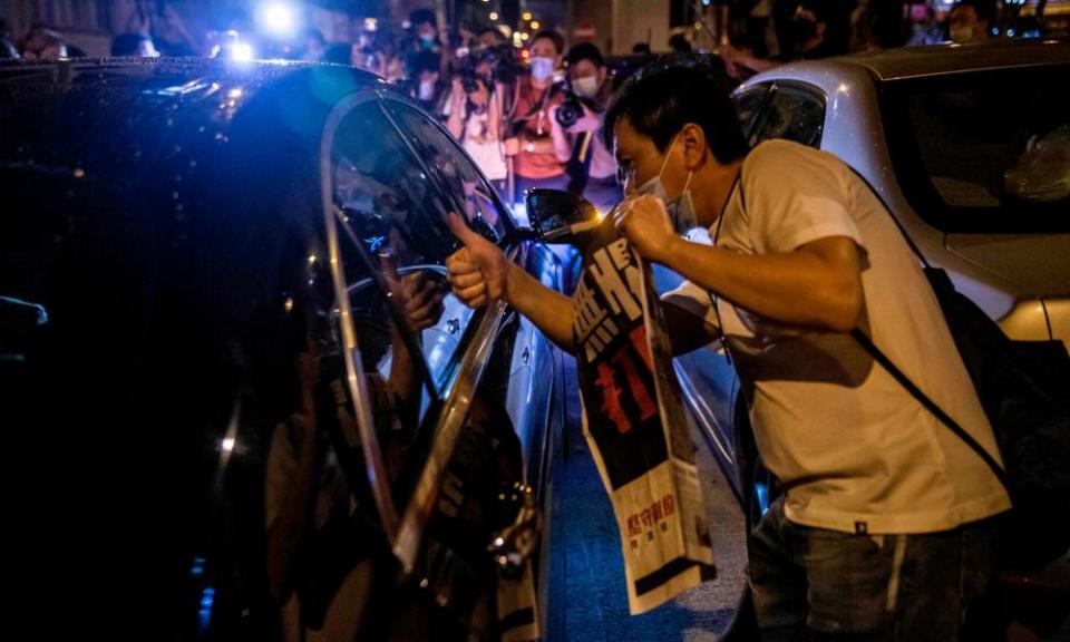 Supporters of Jimmy Lai offer copies of the Apple Daily after his release on bail