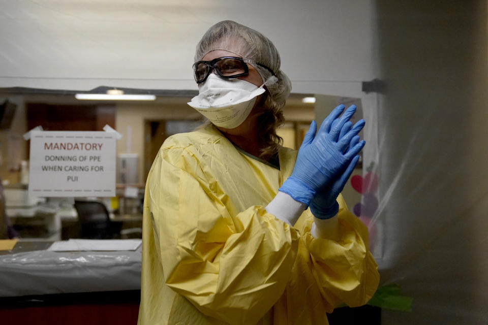 Registered nurse Shelly Girardin prepares to go on rounds after donning personal protective equipment inside an area of Scotland County Hospital sealed off with plastic to care for the influx of COVID-19 patients Tuesday, Nov. 24, 2020, in Memphis, Mo. The coronavirus pandemic is devastating rural hospitals, including the tiny 25-bed facility. (AP Photo/Jeff Roberson)