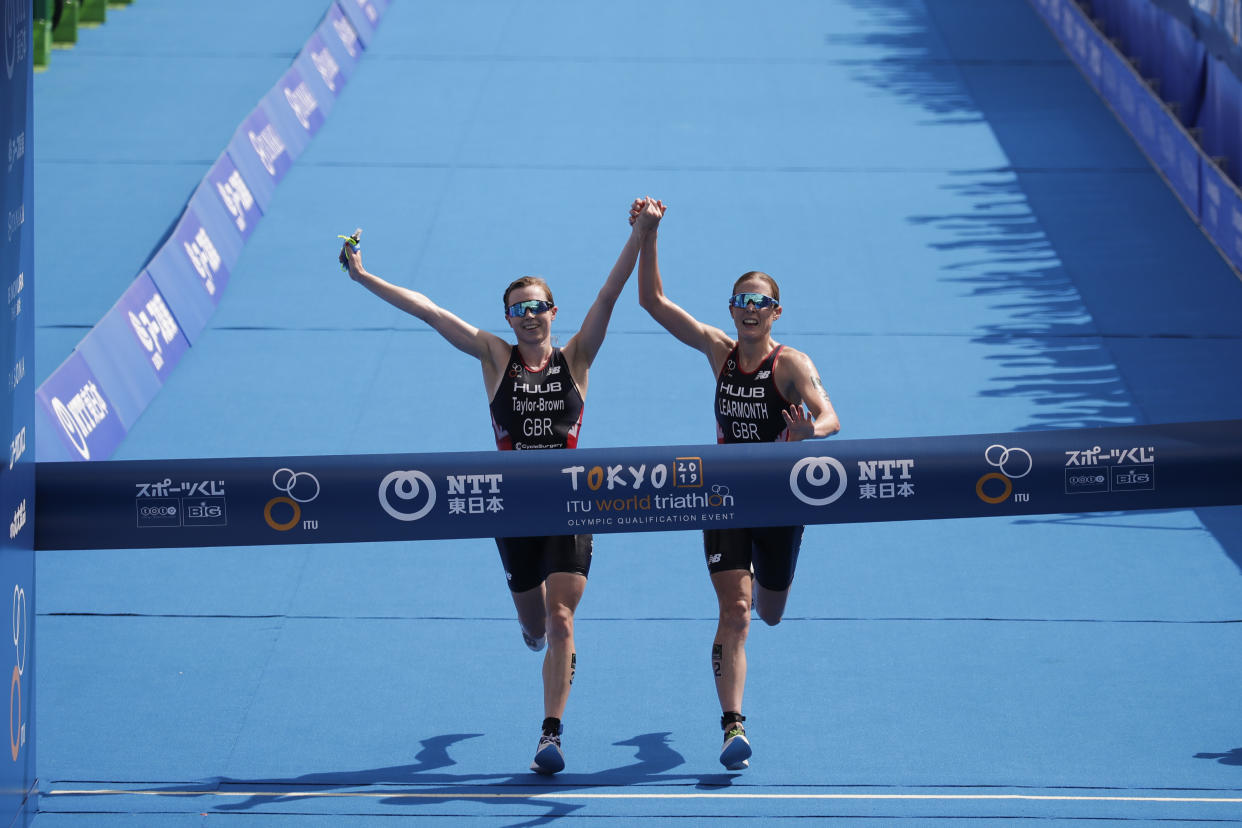 Britain's Georgia Taylor-Brown, left, and Jessica Learmonth hold hands as they cross the finish line during a women's triathlon test event at Odaiba Marine Park, a venue for marathon swimming and triathlon at the Tokyo 2020 Olympics, Thursday, Aug. 15, 2019, in Tokyo. (AP Photo/Jae C. Hong)