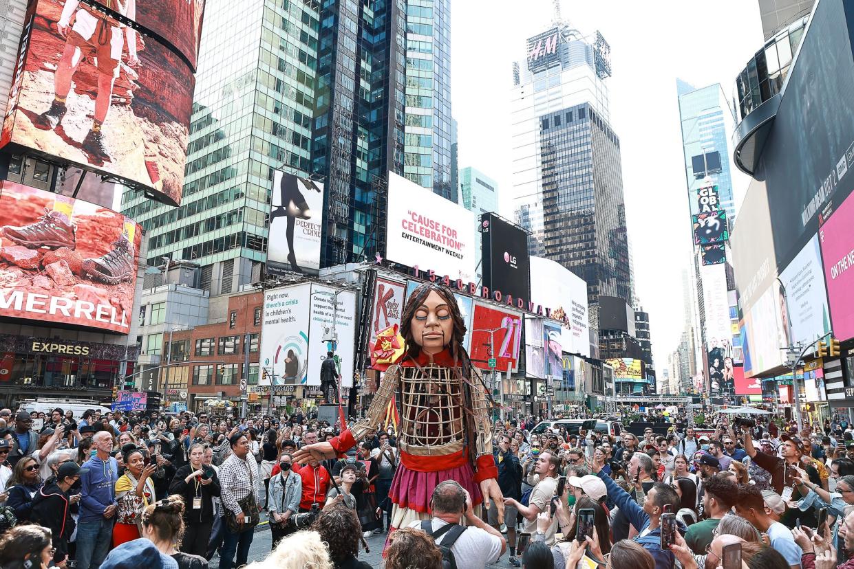 The 12-foot puppet known as "Little Amal" walks through Times Square as onlookers watch on September 16, 2022 in New York City. Little Amal, who has been touring around the world, symbolizes a 10-year-old Syrian girl who is a refugee. The puppet has captured the hearts of people throughout the world while spreading the message of solidarity for displaced people. Little Amal is on a 17-day tour of New York City and will visit a variety of boroughs and neighborhoods while raising awareness about immigration and refugees.