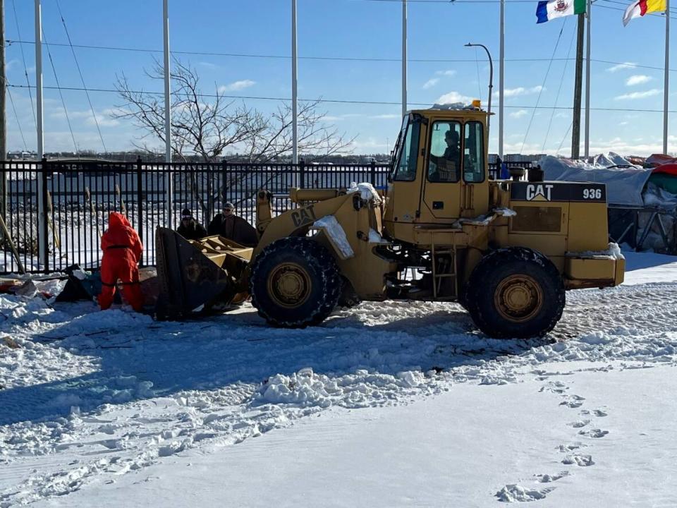 Debris at the Charlottetown Event Grounds encampment is carried away in a front-end loader Wednesday. (Wayne Thibodeau/CBC - image credit)