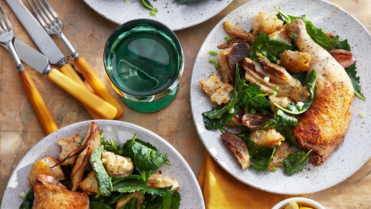 three plates of cider braised chicken and fennel panzanella with cups and silverware