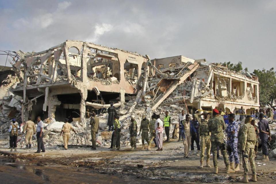 Security officials gather to search for bodies by the devastated shell of a building (AP)