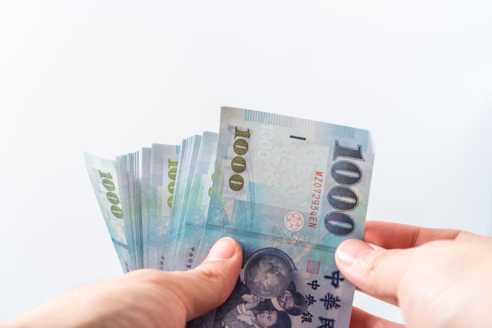 A hand holding a 1000 New Taiwan Dollar bill.