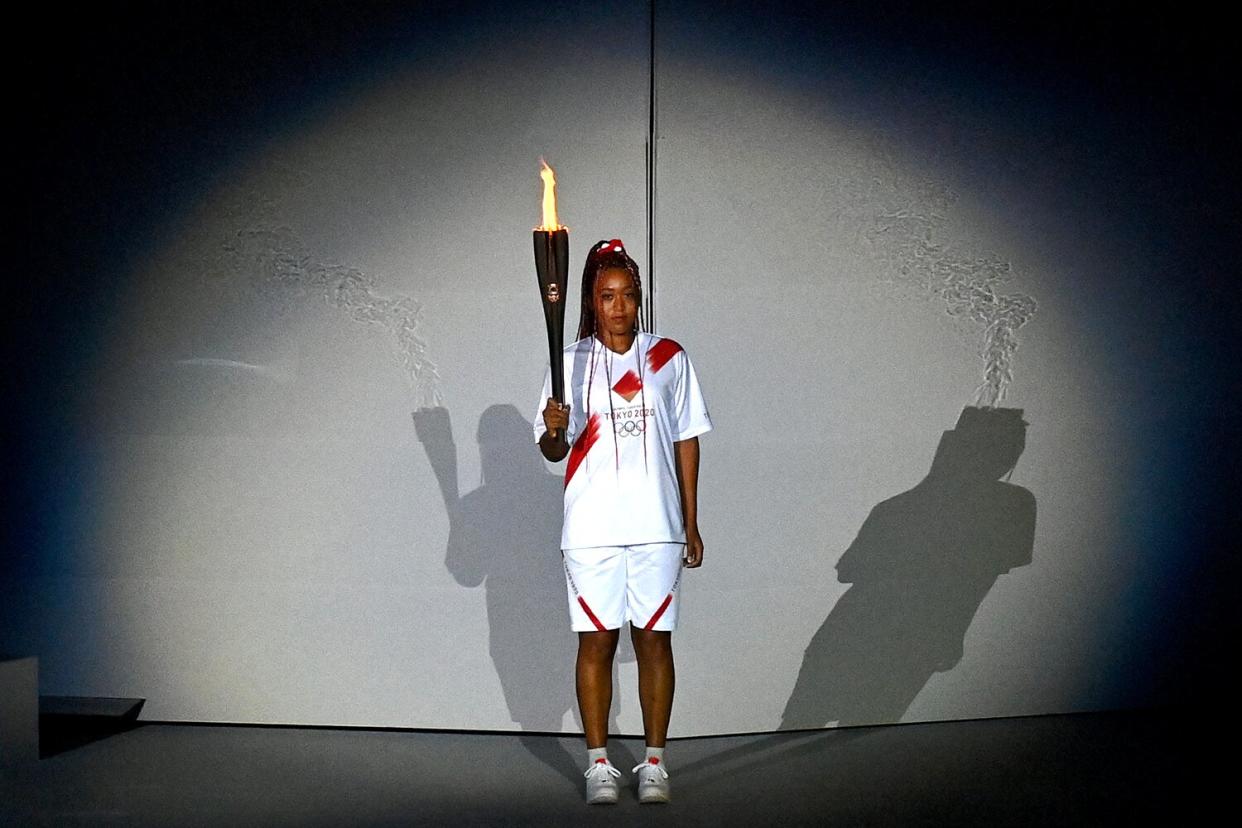 Naomi Osaka of Team Japan is handed the Olympic torch during the Opening Ceremony of the Tokyo 2020 Olympic Games