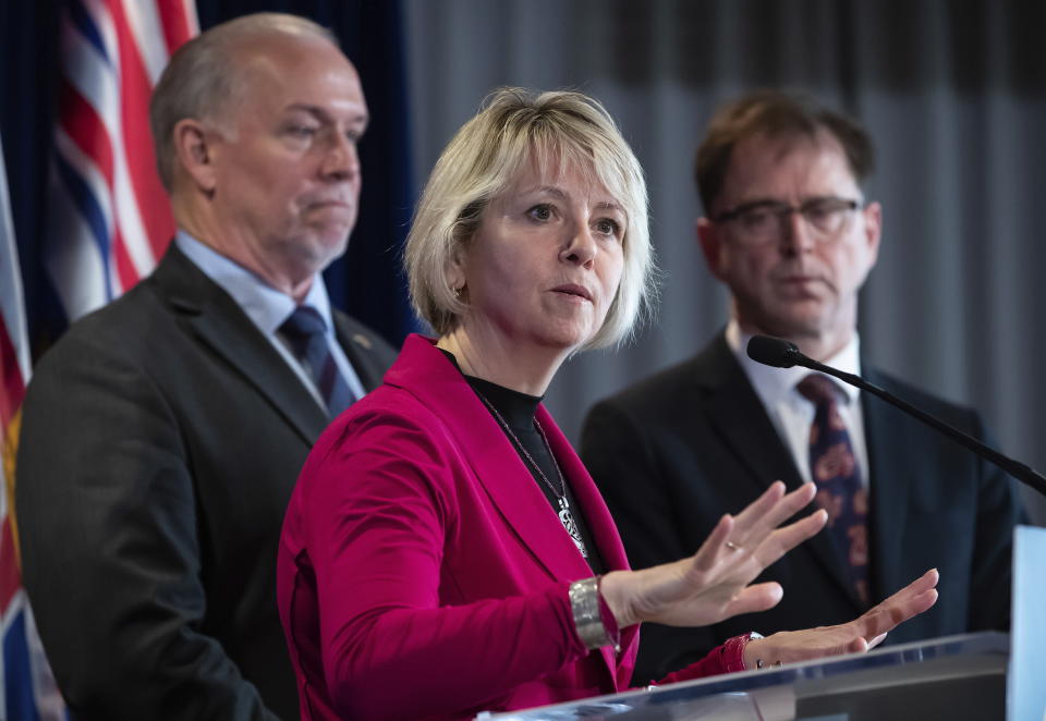 Provincial health officer Dr. Bonnie Henry, centre, responds to questions while British Columbia Premier John Horgan, back left, and Health Minister Adrian Dix listen during a news conference about the provincial response to the coronavirus, in Vancouver, Canada, on Friday, March 6, 2020. (Darryl Dyck/The Canadian Press via AP)