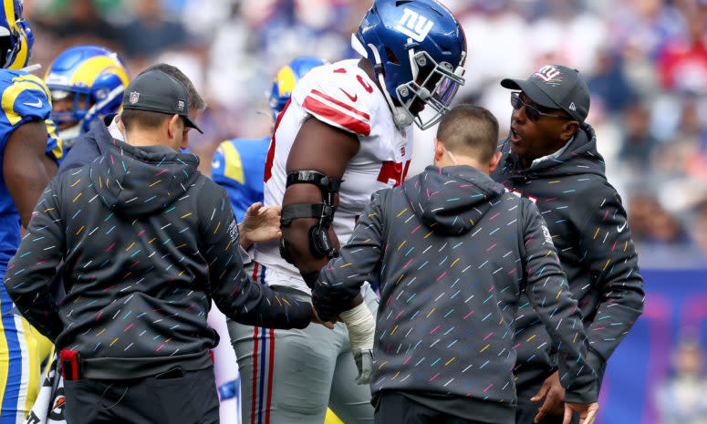 Giants offensive lineman Andrew Thomas limps off the field with trainers.