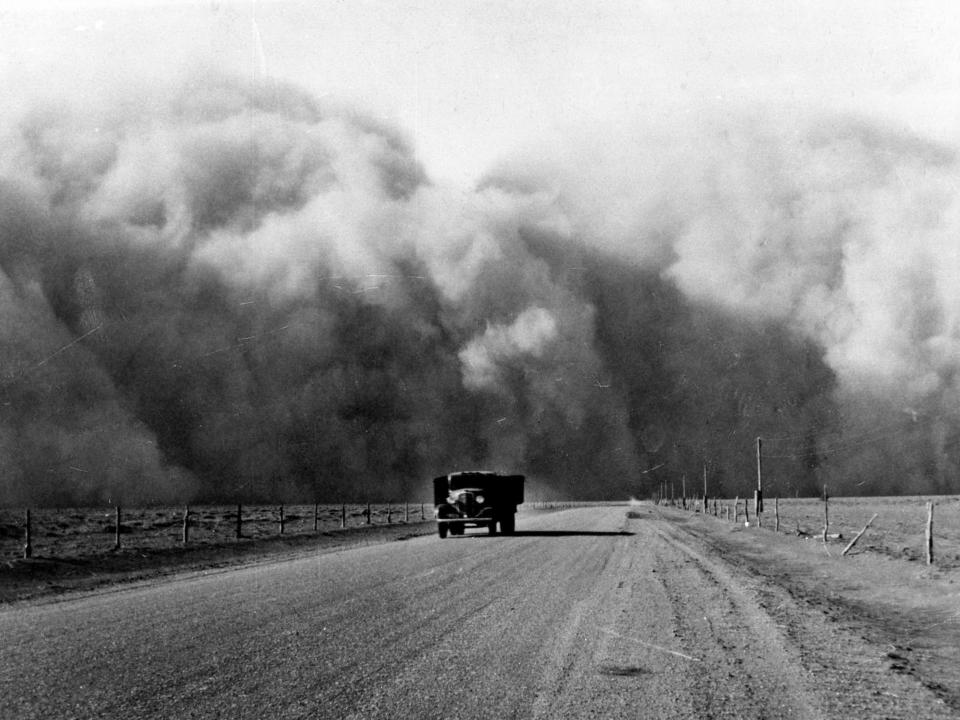 A large dust cloud behind a truck traveling on a highway through Colorado in 1936.