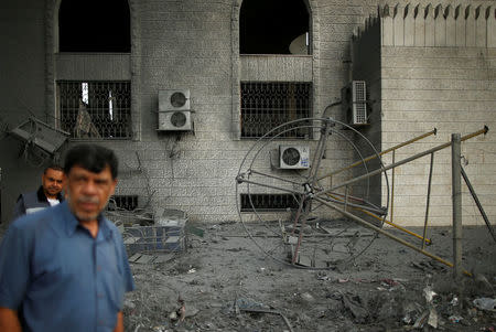 Palestinians pass a swing that was damaged by Israeli air strikes in Gaza City July 15, 2018. REUTERS/Suhaib Salem