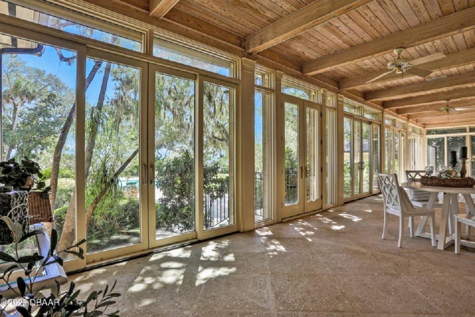 This elevated sunroom stuns with a show-stopping wall of windows overlooking the manicured, park-like grounds, Ralph-Lauren-style pool and deck and the raw beauty of the Intracoastal Waterway.