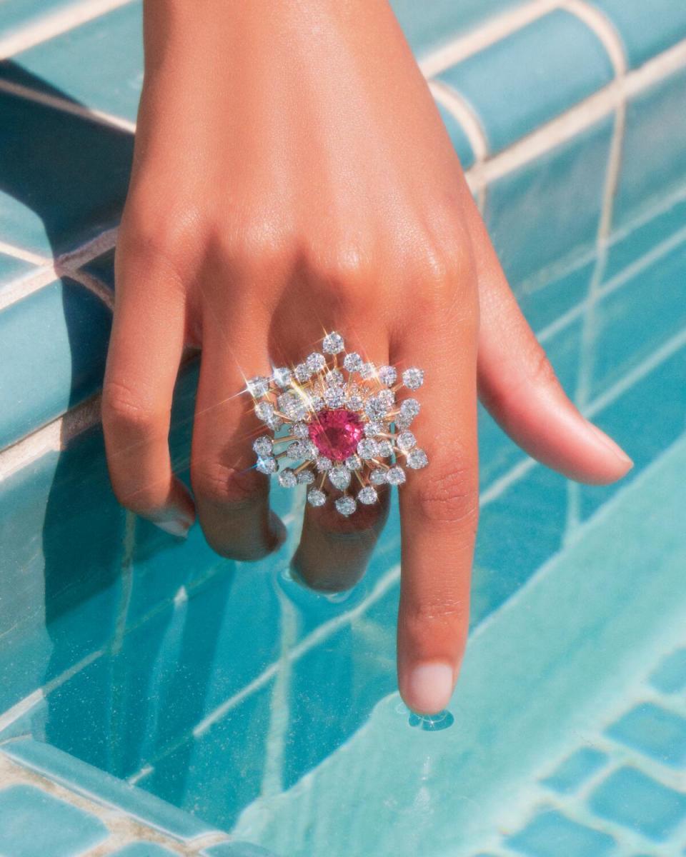 An 18 karat yellow gold with a red spinel of over 5 carats and diamonds shown on a hand grazing water by the pool.