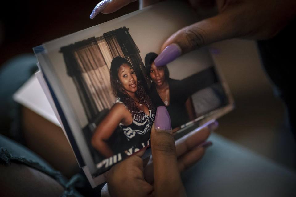 Ansonia Lyons looks at a photograph of her younger self, right in photo, posing with her sister, Angelica Lyons on Saturday, Feb. 5, 2022, in Birmingham, Ala. For decades, frustrated birth advocates and medical professionals have tried to sound an alarm about the ways medicine has failed Black women. Historians trace that maltreatment to racist medical practices that Black people endured amid and after slavery. (AP Photo/Wong Maye-E)