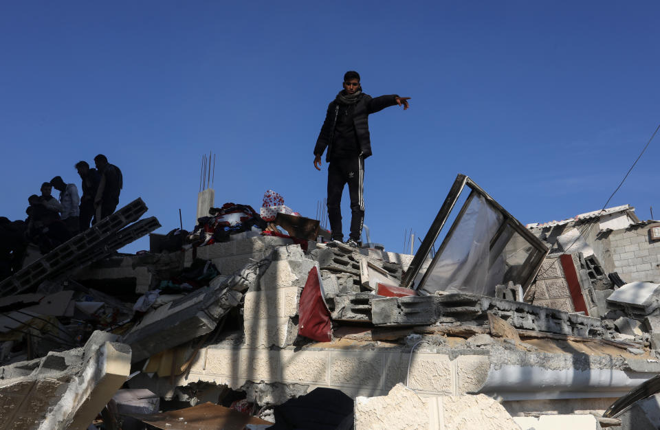 People search for survivors amid the rubble of a collapsed building.