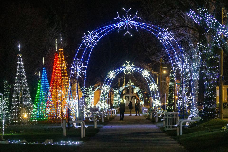 People walk near the light displays for the Light Up The Bluff show Thursday Dec. 9, 2021 in Saint Joseph, Michigan.