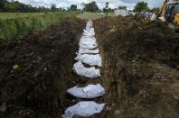ARCHIVO - Un equipo forense entierra a 15 migrantes no identificados que murieron tratando de cruzar el Tapón del Darién en el cementerio de Guayabillo en Agua Fría, Panamá, el 30 de septiembre de 2021. (AP Foto/Arnulfo Franco, Archivo)