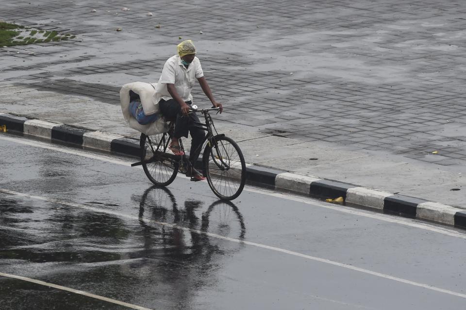 A man rides his bicycle along Marine Drive as rain falls in Mumbai on June 3, 2020. (Photo by PUNIT PARANJPE/AFP via Getty Images)