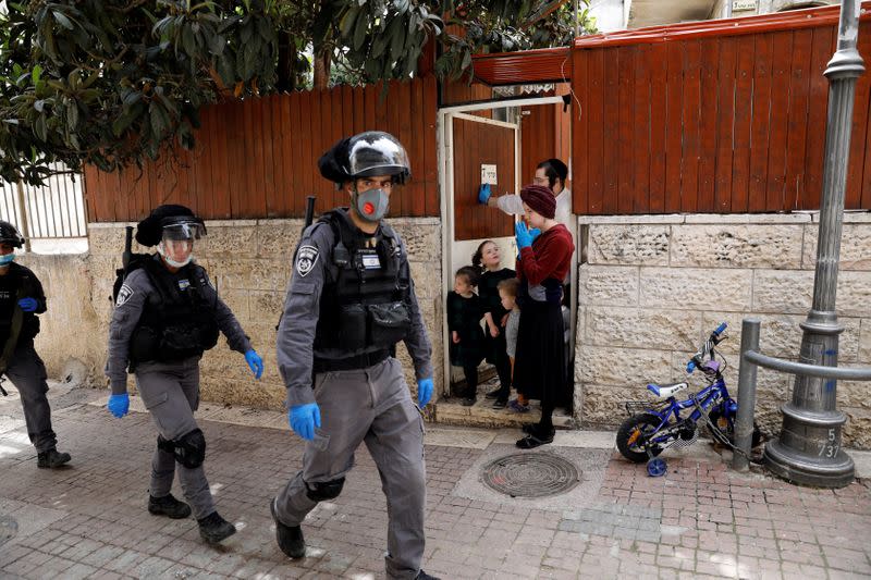An ultra-Orthodox Jewish family watch as Israeli police patrol on the street to enforce a partial lockdown against the coronavirus disease (COVID-19) in Mea Shearim neighbourhood of Jerusalem