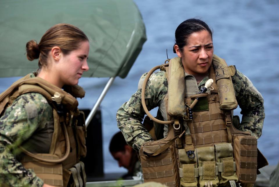 In this Aug. 13, 2013, photo, U.S. Navy Master-at-Arms Third Class Danielle Hinchliff, left, and Master-at-Arms Third Class Anna Schnatzmeyer, listen during training on a Riverine Assault Boat at Camp Lejeune, N.C. It was the first time female participants have received this training as women begin to take on combat roles in the military.