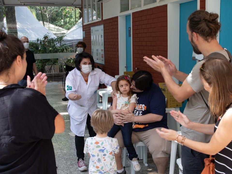 people applaud as girl gets covid vaccine