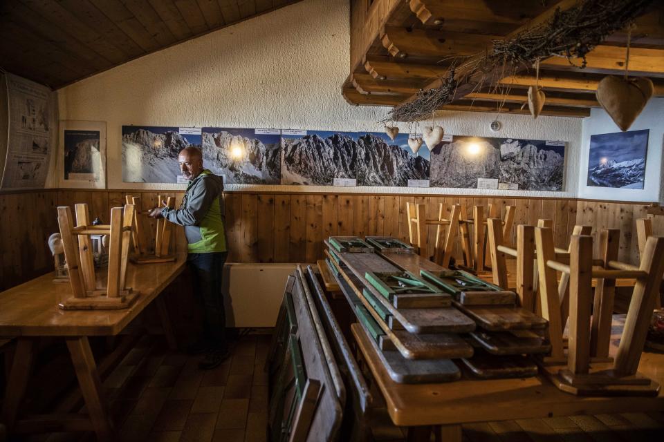 In this image take on Friday, April 24, 2020 Claudio Trentani, 57, moves stools inside his shelter 'Baita Cassinelli', at 1568mt, at the foot of Mt. Presolana, in Castione della Presolana, near Bergamo, northern Italy. On Saturday, March 7, 2020, a day before the national lockdown was announced, he had over 100 people for lunch and was sincerely worried about the risks of infection. Now he is waiting to see if he can reopen under new laws applicable to restaurants, but with his indoor area of about 60 mq he is hoping to make the most of his outdoor space. (AP Photo/Luca Bruno),