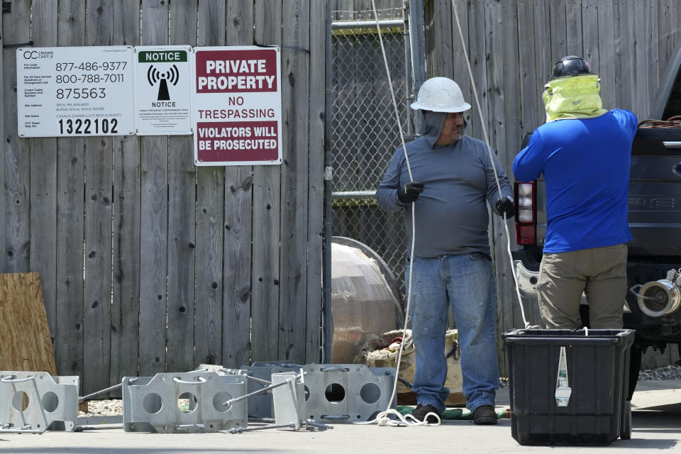 FILE - Workers in hot weather work at a Radio Frequency Environment area in Riverwoods, Ill., Monday, June 17, 2024. While a heat wave brings the hottest temperatures so far this year to the Midwest and Northeast, forecasters also are discussing heat domes. What's the difference? A heat dome forms when high pressure in the upper atmosphere causes the air below it to sink, heat up and expand. (AP Photo/Nam Y. Huh, File)