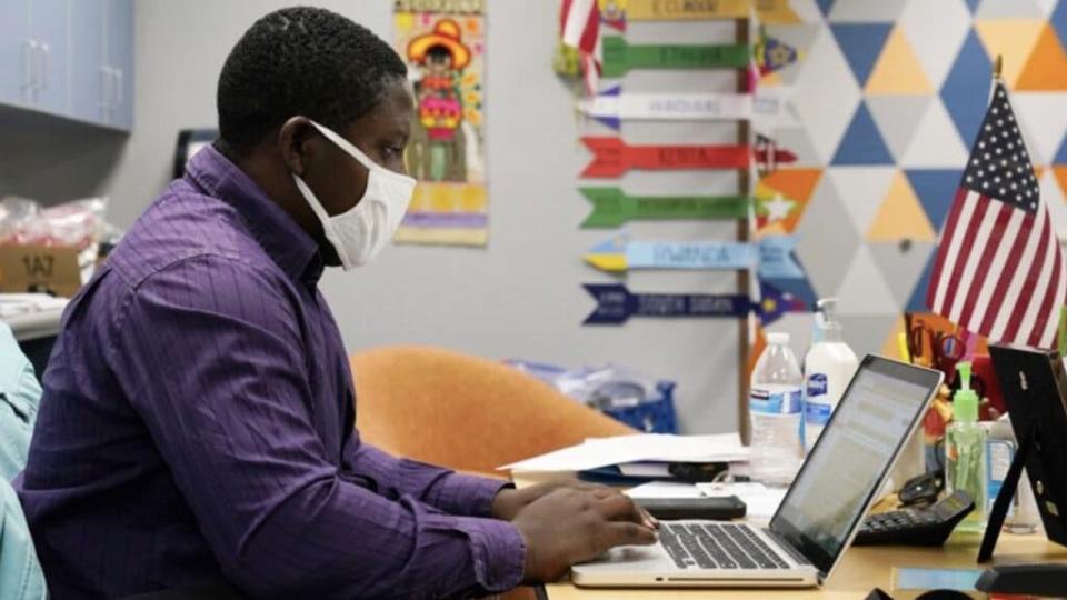 Teaching assistant Samuel Lavi helps out with an online class at the Valencia Newcomer School, Tuesday, Sept. 2, 2020, in Phoenix. Communicating during the coronavirus pandemic has been trying for parents and students at the Phoenix school for refugees who speak a variety of languages and are learning to use technology like iPads and messaging apps. (via AP/ Ross D. Franklin)