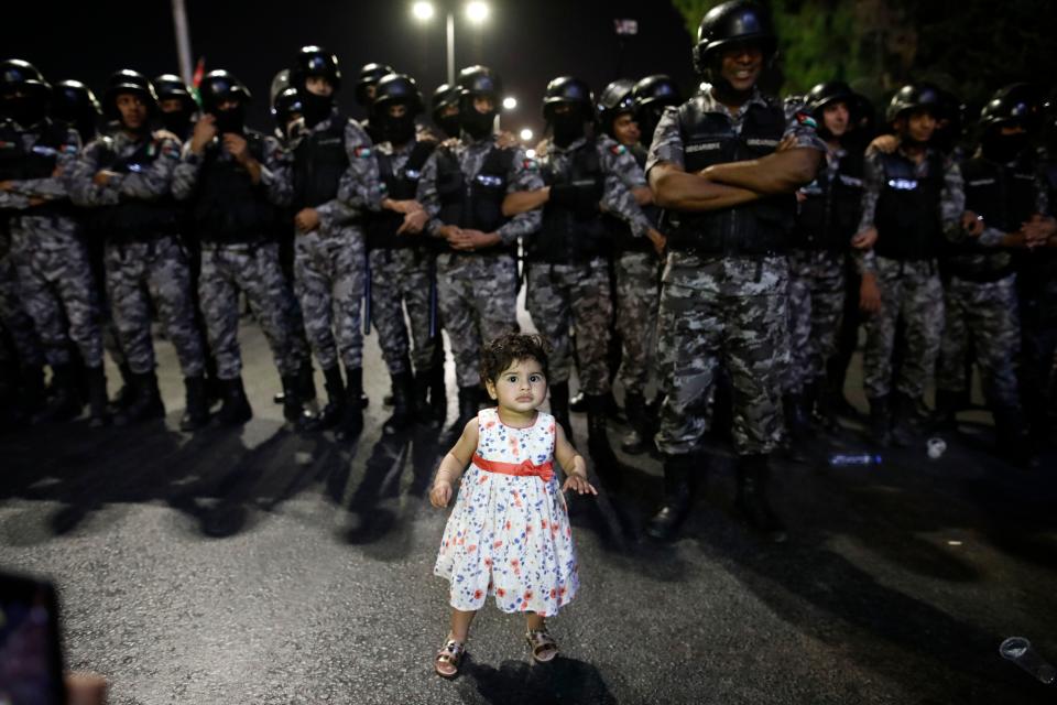 <p>A young girl stands in front of Jordanian anti-riot police during a protest near the prime minister’s office in Amman, Jordan, on June 5, 2018. (Photo: Ahmad Gharabli/AFP/Getty Images) </p>