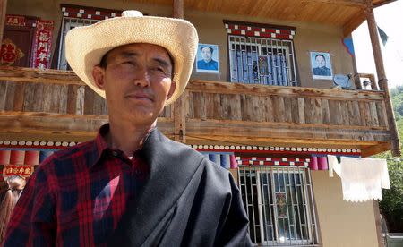 A guest house owner poses in front of his property with posters of China's late Chairman Mao Zedong and leader Deng Xiaoping on the wall, in Aba Tibetan and Qiang Autonomous Prefecture, Sichuan province, July 30, 2015. REUTERS/Natalie Thomas