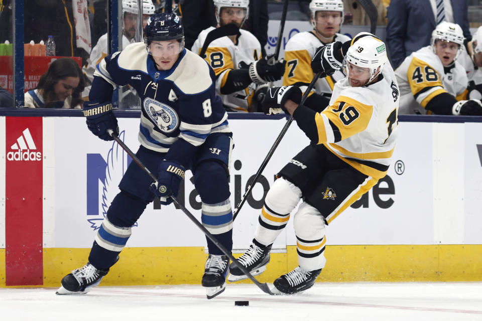 Columbus Blue Jackets defenseman Zach Werenski, left, chases the puck in front of Pittsburgh Penguins forward Reilly Smith (19) during the second period of an NHL hockey game in Columbus, Ohio, Saturday, March 30, 2024. (AP Photo/Paul Vernon)