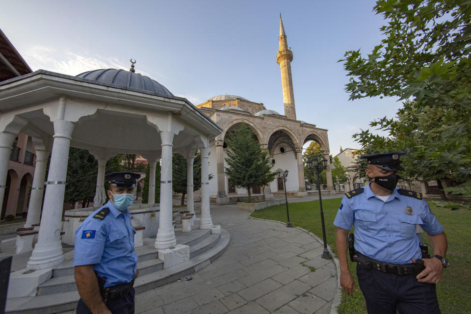 Kosovo police officers stand outside the Sultan Mehmet Fatih mosque in Pristina, Kosovo, Friday, July 31, 2020. Government measures banned all public gatherings including religious due to fear of recent uprise in COVID-19 cases. (AP Photo/Visar Kryeziu)