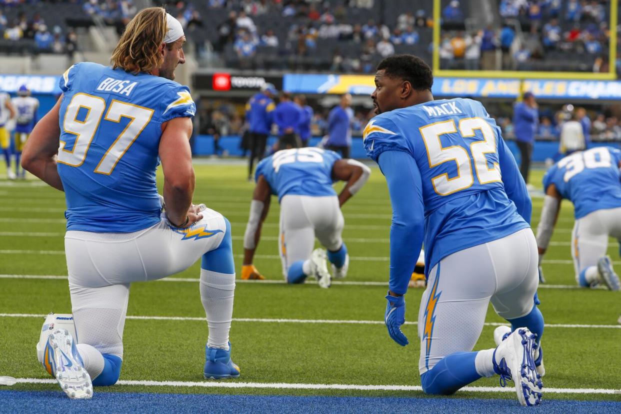 Chargers defensive stars Joey Bosa (left) and Khalil Mack kneel on the goal line.