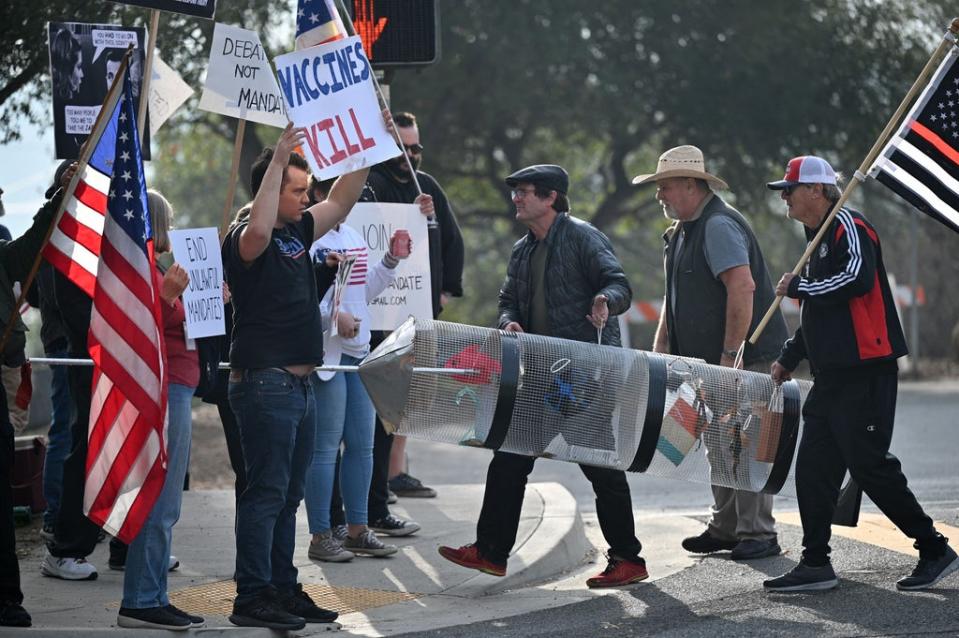 Workers at Nasa’s Jet Propulsion Laboratory (JPL) and their supporters carry a representation of a syringe during a protest on 1 November outside JPL in Pasadena, California against a US government mandate requiring all federal employees to received the Covid-19 coronavirus vaccine (AFP via Getty Images)