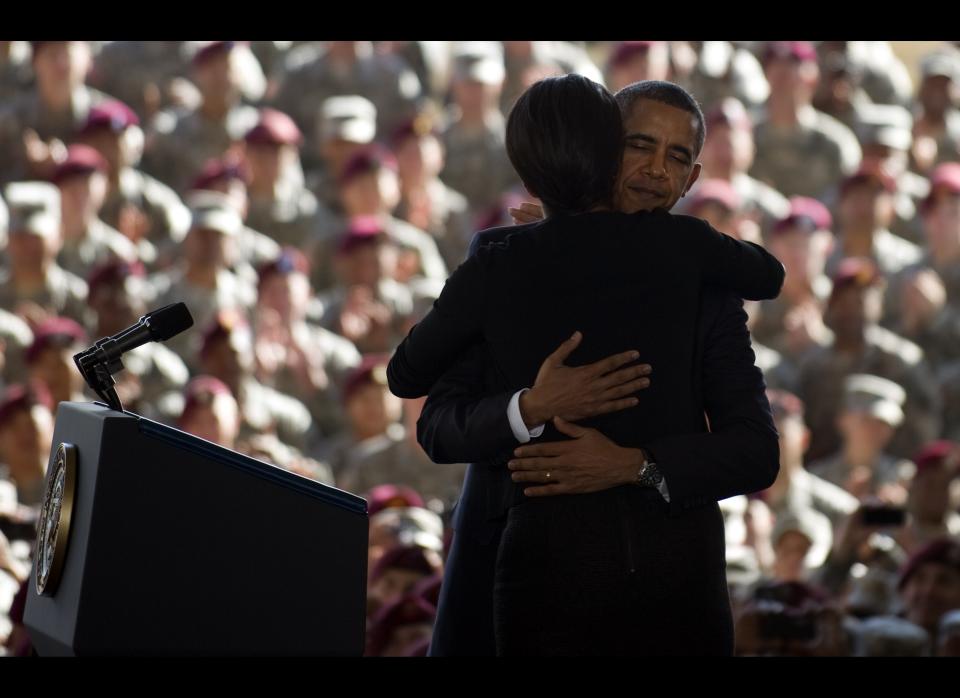 First Lady Michelle Obama (C) is hugged by US President Barack Obama as they deliver remarks to troops and military families at Fort Bragg, NC, December 14, 2011.    Obama on Wednesday marked the US exit from Iraq by eulogizing fallen troops and seek to move Americans on from a divisive near nine-year war which he opposed. AFP PHOTO/Jim WATSON (Photo credit should read JIM WATSON/AFP/Getty Images)