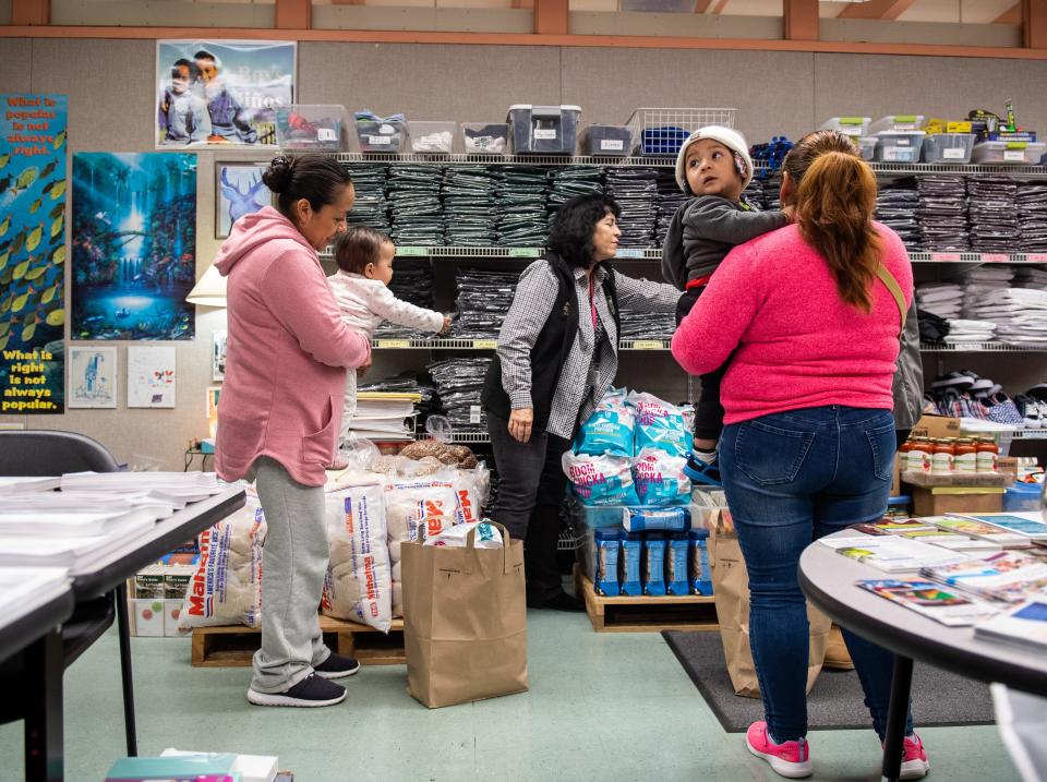 Two mothers hold their babies as they receive food and clothes from the Salinas School District Family Resource Center  located in Sherwood Elementary School on Dec. 17, 2019.