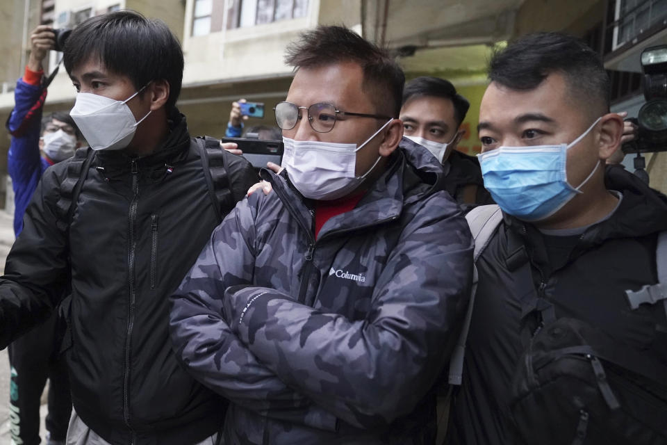 CORRECTS THE FIRST NAME TO RONSON FROM ROBSON - Senior editor of "Stand News" Ronson Chan, center, is arrested by police officers in Hong Kong, Wednesday, Dec. 29, 2021. Hong Kong police said they arrested several of its staff, including Chan, who is also head of the Hong Kong Journalists Association, early Wednesday morning for conspiracy to publish a seditious publication. (AP Photo)