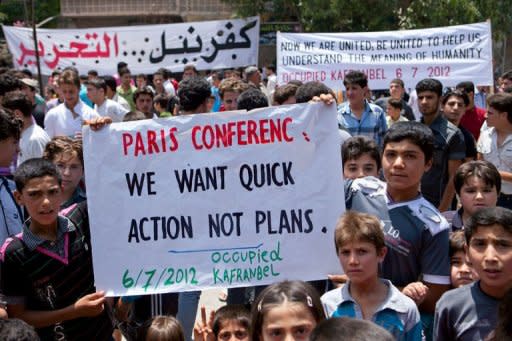 Syrian boys hold a banner about the international conference on the Syrian crisis being held in Paris during a demonstration after Friday prayers in Kfar Nubul in the northwestern province of Idlib