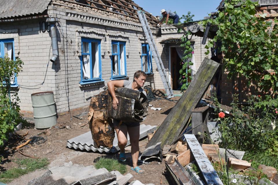 A woman takes out the debris from a house damaged by Russian shelling in Kushuhum, near Zaporizhia (AP)