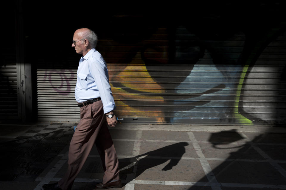 An elderly man walks past a graffiti in central Athens on Monday, June 15, 2015.  AP Photo/Petros Giannakouris)