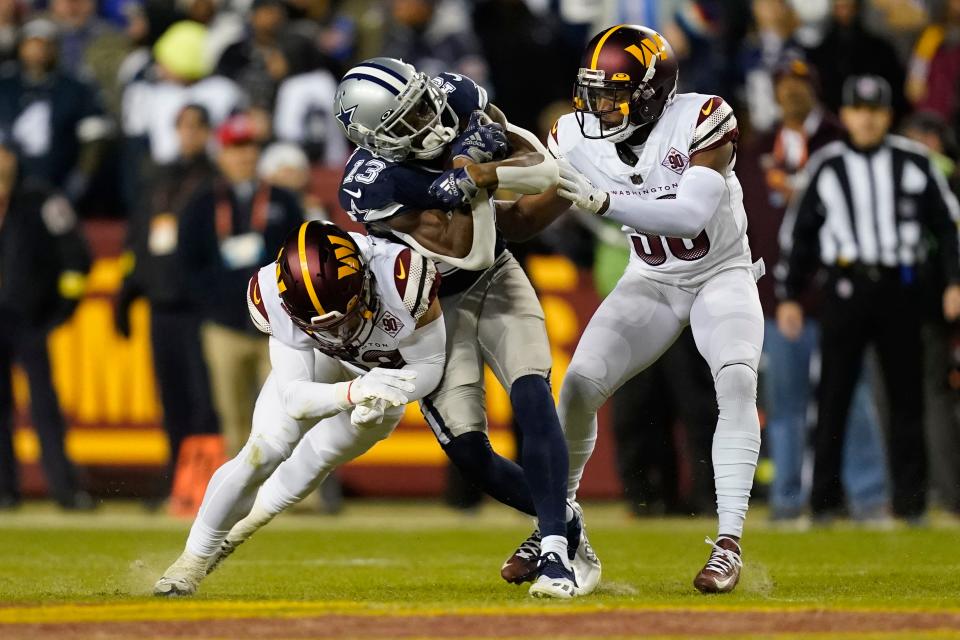 Dallas Cowboys wide receiver Michael Gallup is tackled by Washington Commanders defensive backs Darrick Forrest, left, and Danny Johnson during Washington's win on Sunday. The Cowboys will play at Tampa Bay in an NFC wild-card game.