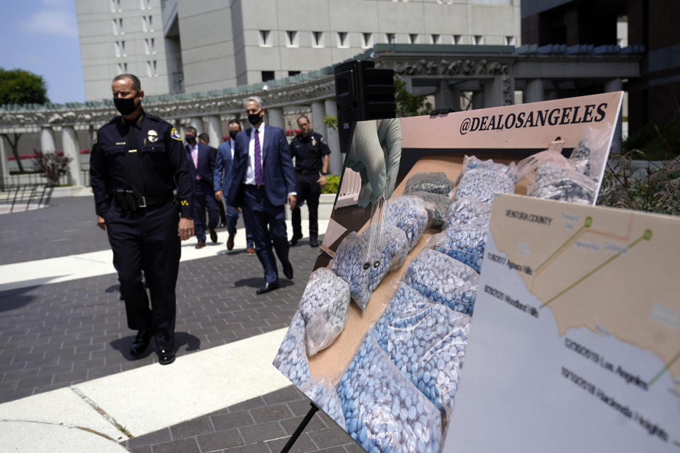 FILE - Officials walk past images of illegal drugs outside the Edward R. Roybal Federal Building on May 13, 2021, in Los Angeles. Authorities say a teenage girl died Tuesday night, Sept. 13, 2022, of an apparent overdose at a Los Angeles high school and police are investigating three other possible fentanyl overdoses in the area. (AP Photo/Marcio Jose Sanchez, File)