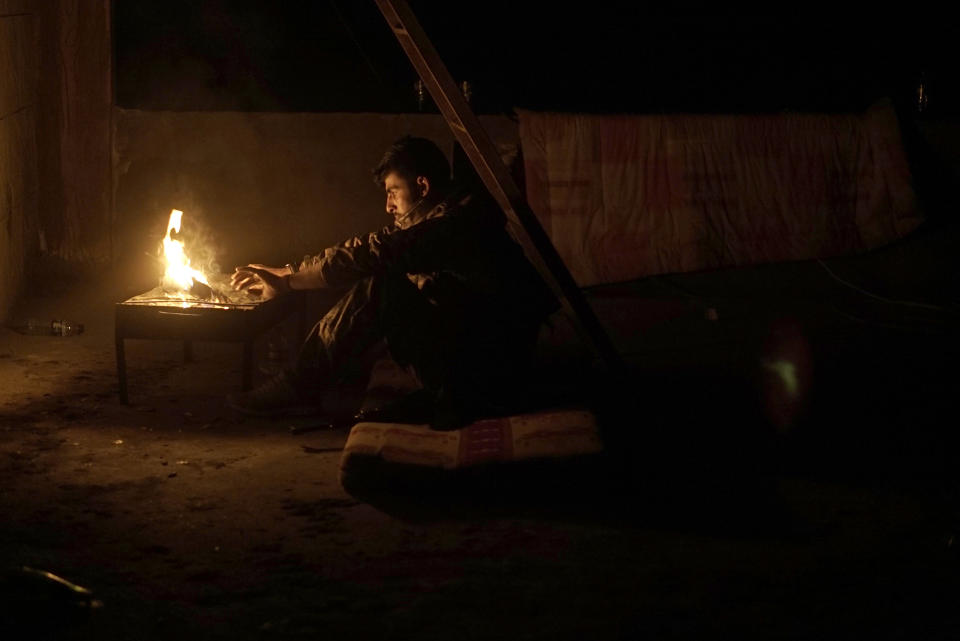 A U.S.-backed Syrian Democratic Forces (SDF) soldier warms himself by a fire on a rooftop position as fighting resumes to wrest Islamic State militants from Baghouz, Syria, Monday, March 11, 2019. (AP Photo/Maya Alleruzzo)