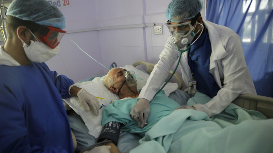 A patient with the novel coronavirus is cared for by two medical staff.